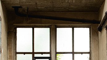 Foto eines minimalistischen Stuhls aus Stein in einem verlassenen Raum