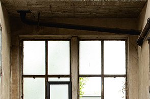 Foto eines minimalistischen Stuhls aus Stein in einem verlassenen Raum