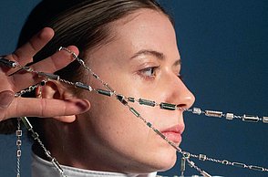 Eine Frau hält eine Perlenkette an ihrem Gesicht