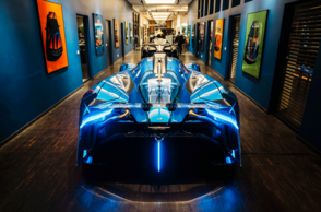 Ein ausgestelltes Auto leuchtet mit Lichtern. An den Wänden hängen weitere Bilder von Autos