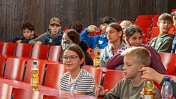 Workshopsituation: Kinder sitzen auf Plätzen und schreiben.