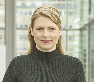 Frau mittleren Alters, mit blonden Haaren, schaut in die Kamera.