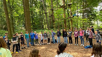 Kinder machen eine Teamübung im Waldklettergarten