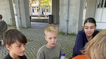 Kinder sitzen um einen Tisch mit Stift und Papier