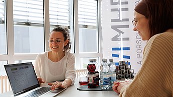 Zwei Personen im Gespräch, auf einen Laptop schauend