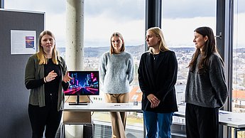 4 Studentinnen präsentieren ihre Ergebnisse zum Motto "Neue Welten". Sie hatten unterschiedliche Welten erstellt, in der es jeweils nur die folgenden Musikrichtungen gibt: Pop, Rock, Klassik, Techno, Indie, Country und Reggae. Diese Unterscheiden sich in Opik, Architektur und menschlichem Verhalten.