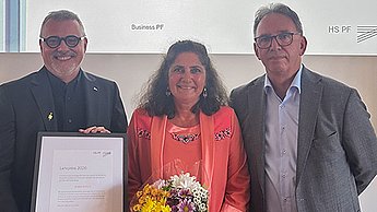 Preisträgerin Brigitte Burkart mit einem Blumenstrauß in der Hand, links von ihr steht Prof. Dr. Thomas Cleff mit Urkunde, rechts davon Prof. Dr. Marcus-Oliver Schwaab