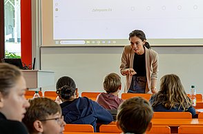 Kinder lernen Marktforschung. Professorin erklärt Fragestellungen zum Thema Eis.