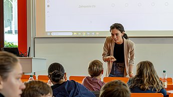 Kinder lernen Marktforschung. Professorin erklärt Fragestellungen zum Thema Eis.