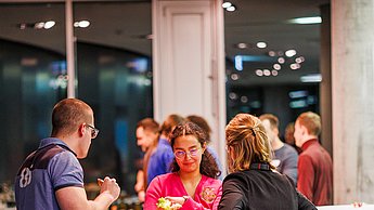 Studierende unterhalten sich an einem Stehtisch