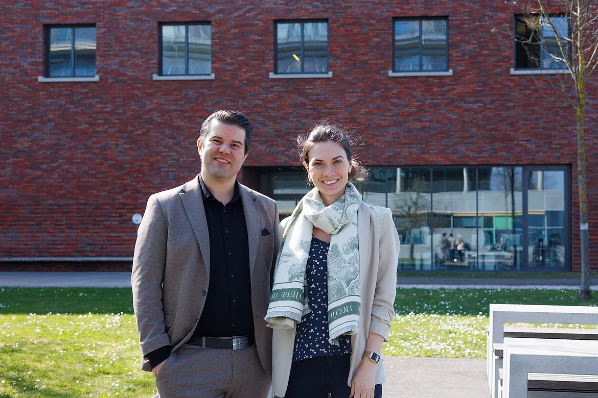 Ein Mann und eine Frau (Professor*innen der Hochschule Pforzheim) schauen lächelnd in die Kamera