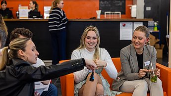 Studierende sitzen auf einem Sofa und betrachten Produktproben