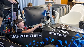 Ein Junge sitzt im Rennsimulator und lächelt.