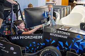 Ein Junge sitzt im Rennsimulator und lächelt.