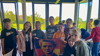 Die erste Gruppe an Kindern präsentiert ihr Bild von Marie Curie