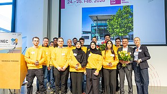 Gruppenfoto von jungen Menschen in gelben Sweatshirts und Jörg Woidasky mit Blumenstrauß