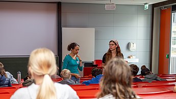 Workshopsituation: Kinder sitzen auf Plätzen und schreiben.