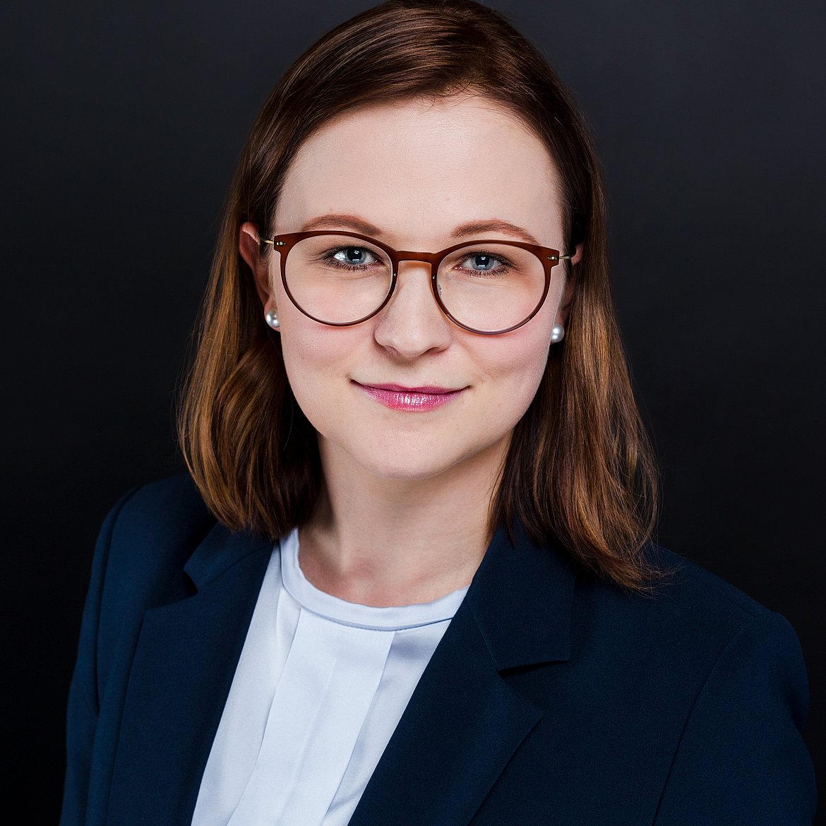Frau mit Brille schaut freundlich in die Kamera